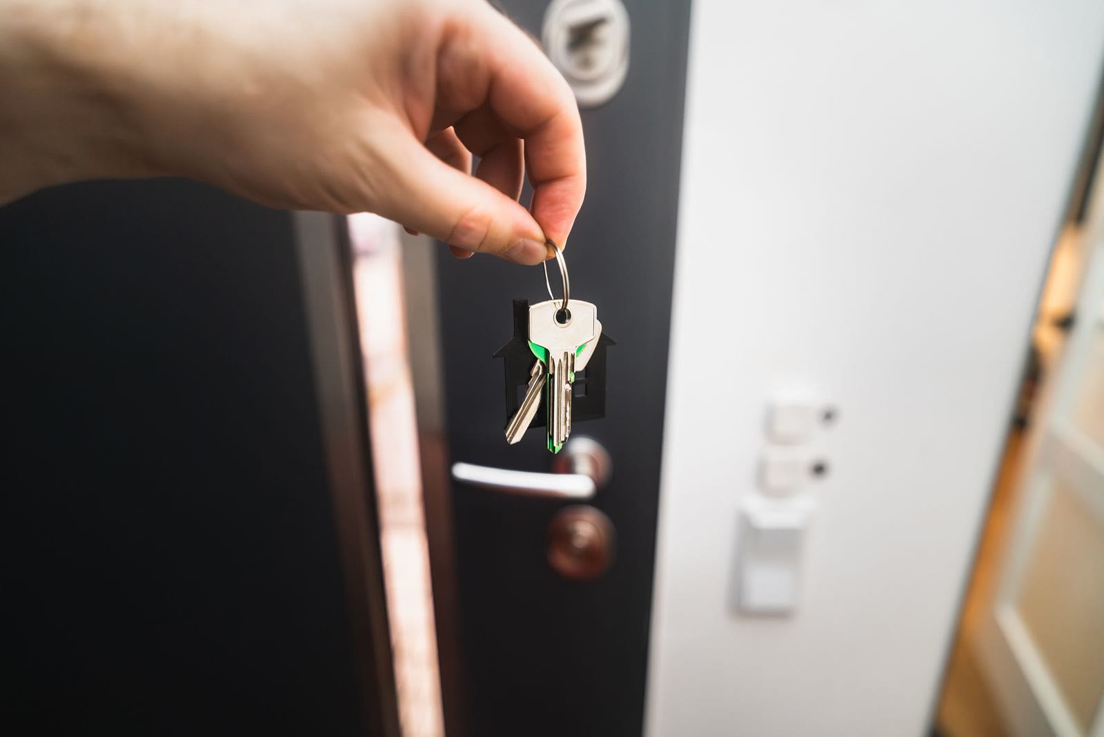 A realtor handing new homeowners the keys at their front door